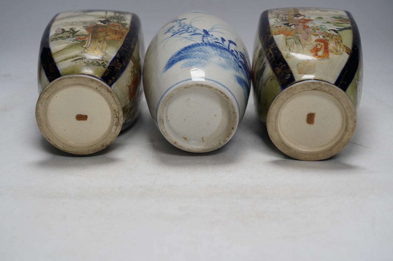 A pair of Japanese satsuma pottery vases and a blue and white Meiji Arita vase, largest 24cm high. Condition - fair